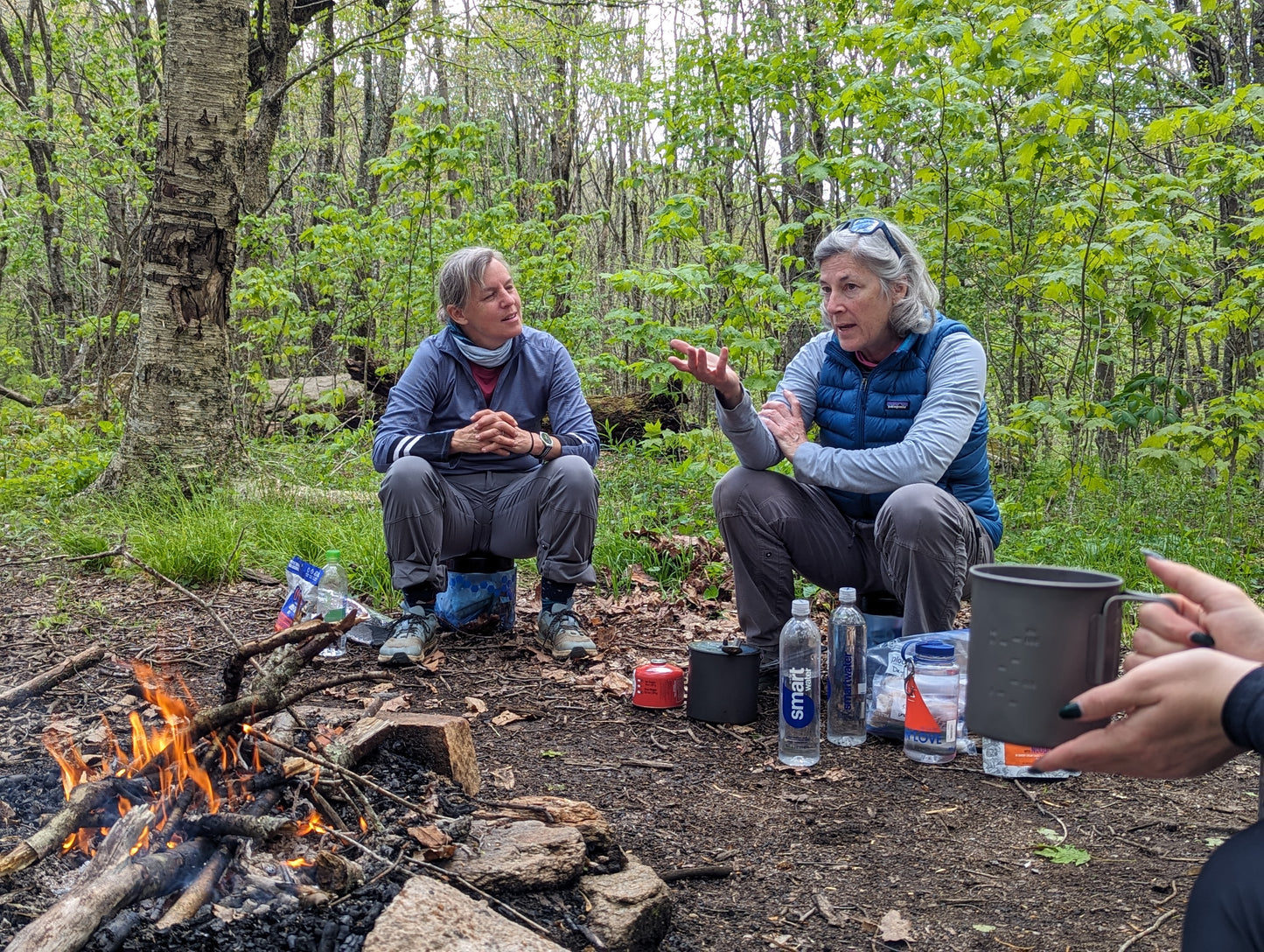 Two women sitting around a campfire having a conversation
