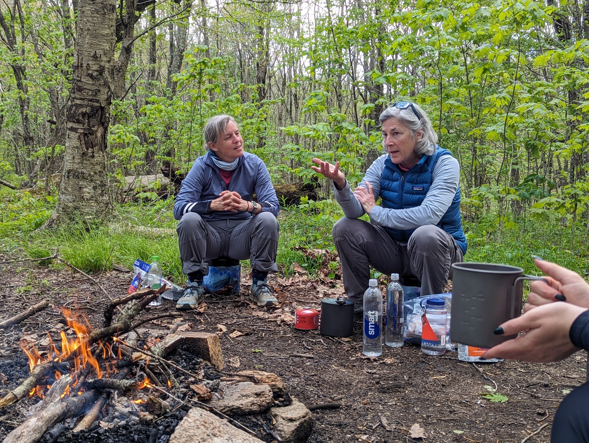 Two women sitting around a campfire having a conversation