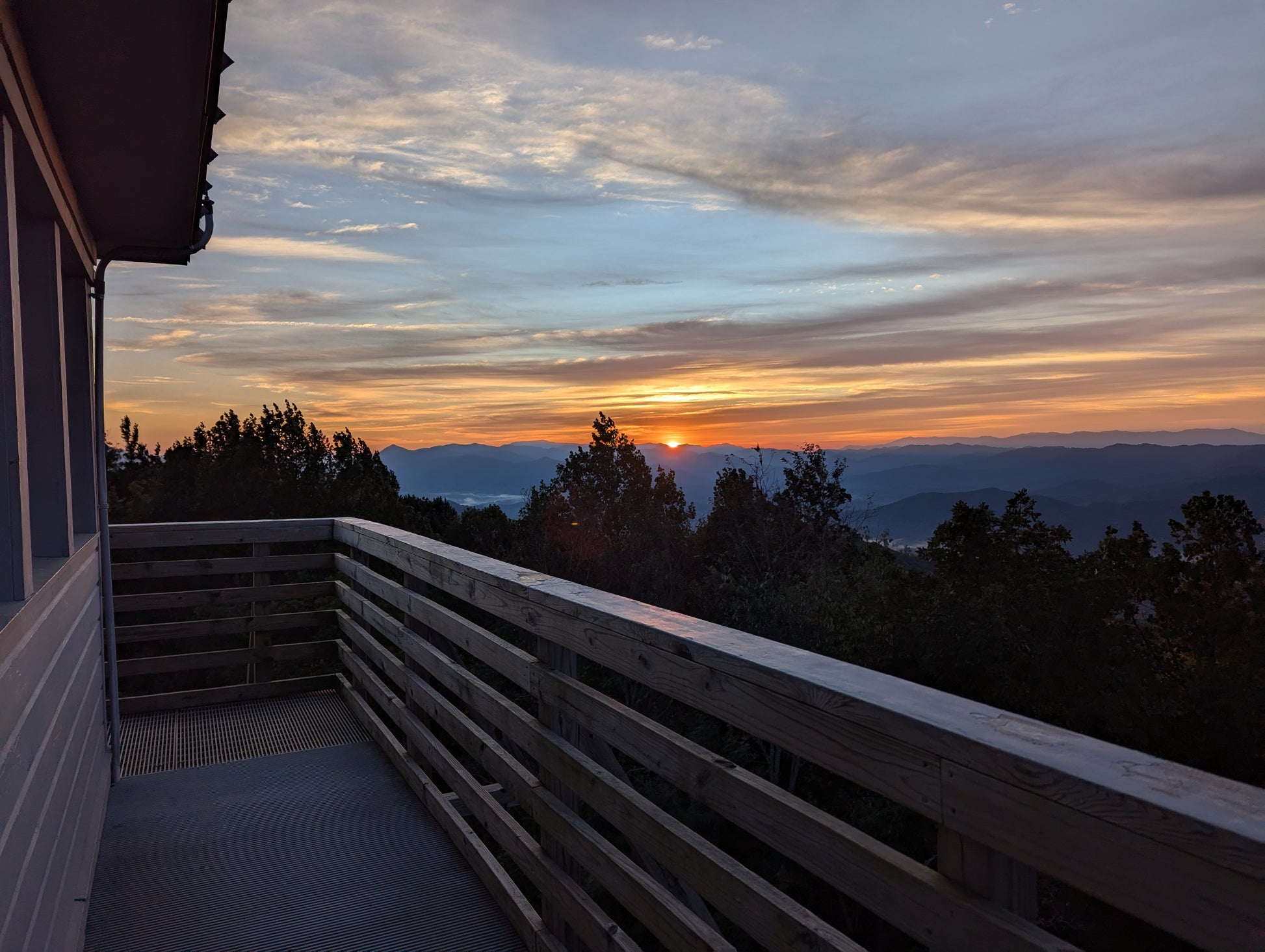A sunset over the mountains viewed from the top of a wooden fire tower